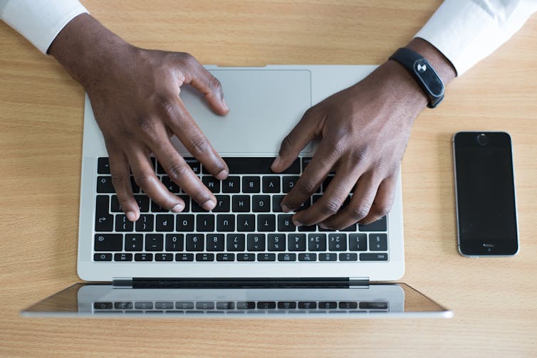 Deux mains tapant sur un ordinateur portable